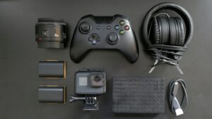 Top view of various gaming and tech gadgets, including a controller and headphones.